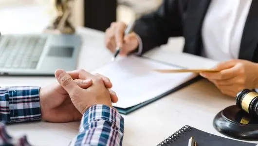 Client with clasped hands as a lawyer takes notes