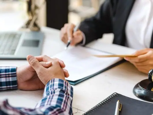 Client with clasped hands as a lawyer takes notes