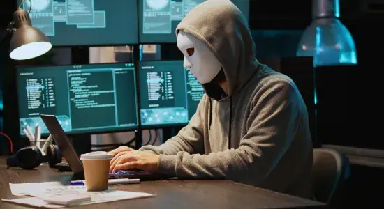 Masked person at a computer committing online fraud