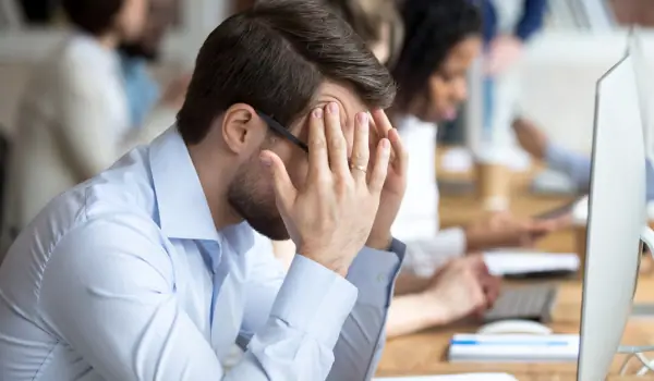 Stressed worker with head in hands at an office desk