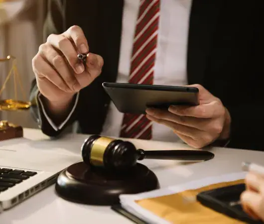 Lawyer reviewing case papers on a tablet beside a gavel