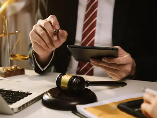 Defence lawyer reviewing case papers on a tablet beside a gavel
