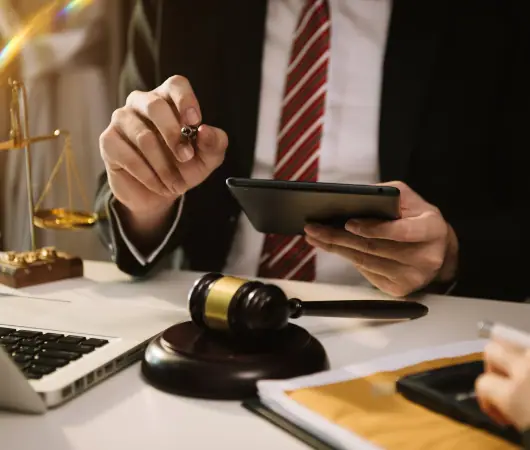Lawyer reviewing case papers on a tablet beside a gavel