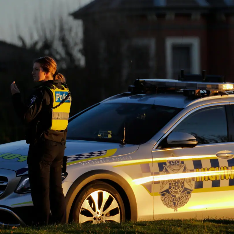 Victoria Police officer beside a highway patrol car