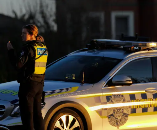 Victoria Police officer beside a highway patrol car
