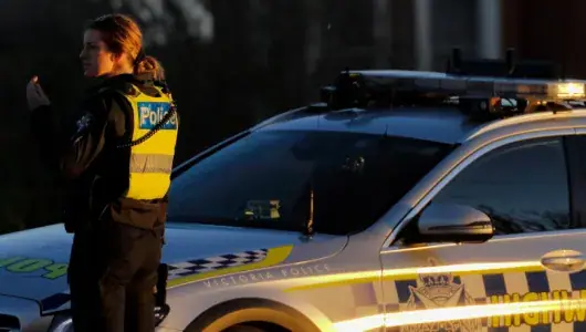 Victoria Police officer beside a highway patrol car