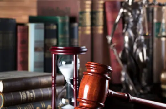 Gavel, hourglass and a statue of Justice in front of law books