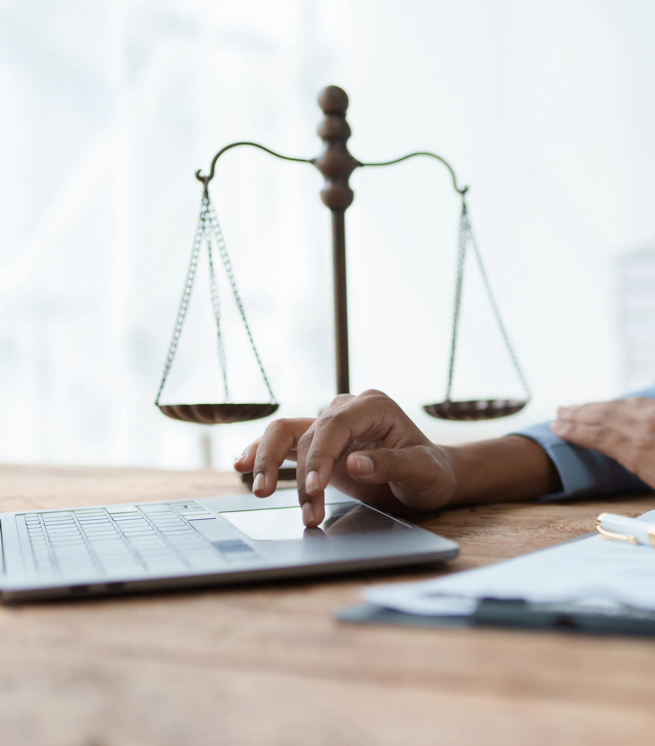 Lawyer using a laptop beside brass scales of justice
