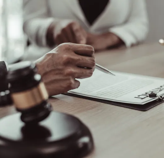 Client signing legal documents with a lawyer, gavel in the foreground