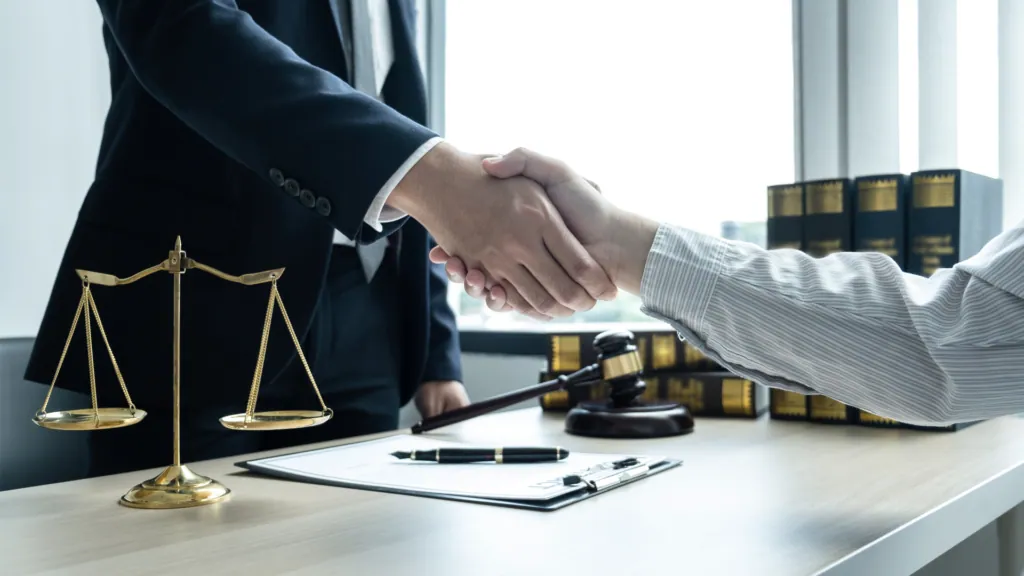 Lawyer shaking hands with a client beside scales of justice