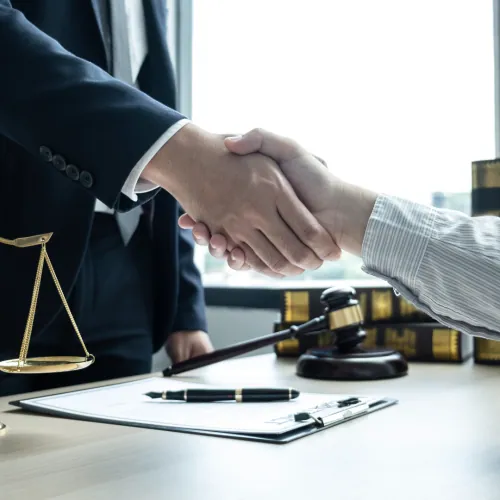Lawyer shaking hands with a client beside scales of justice