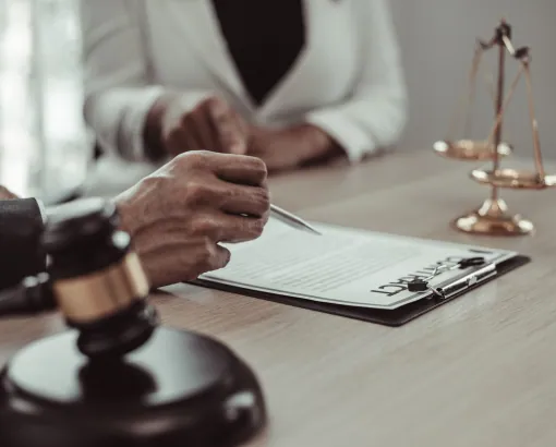Client signing legal documents with a lawyer, gavel in the foreground
