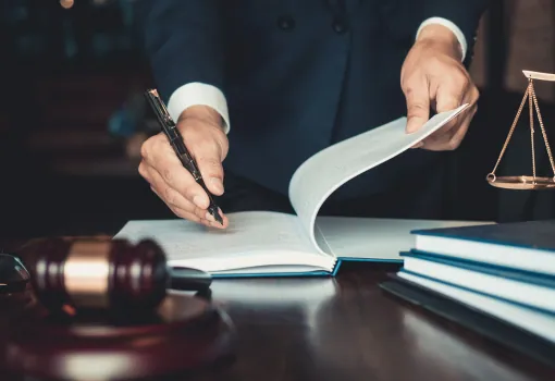 Lawyer turning the pages of a law book beside a gavel and scales