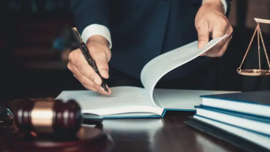 Lawyer turning the pages of a law book beside a gavel and scales