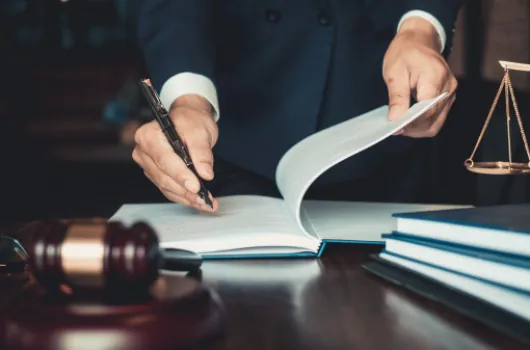 Lawyer turning the pages of a law book beside a gavel and scales