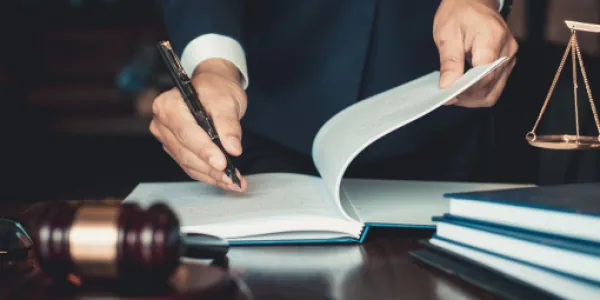 Lawyer turning the pages of a law book beside a gavel and scales