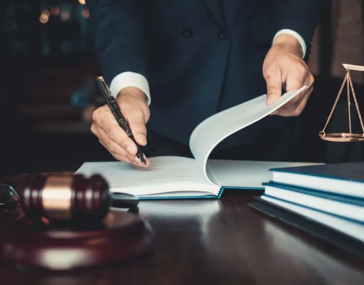 Lawyer turning the pages of a law book beside a gavel and scales