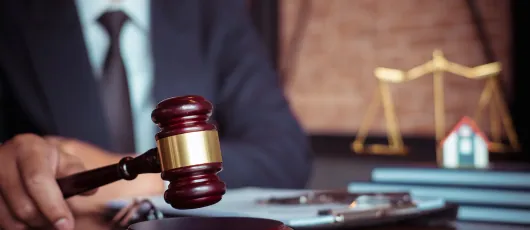 Lawyer holding a gavel at a desk beside scales of justice