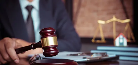 Lawyer holding a gavel at a desk beside scales of justice