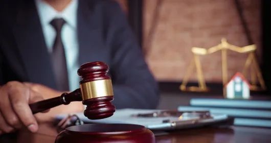 Lawyer holding a gavel at a desk beside scales of justice