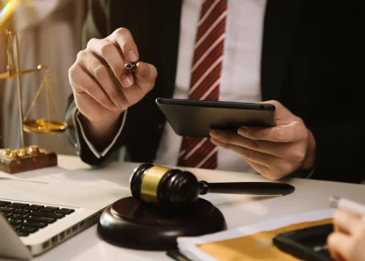 Lawyer reviewing case papers on a tablet beside a gavel