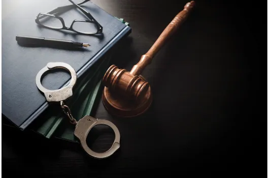 Handcuffs and a gavel resting on law books
