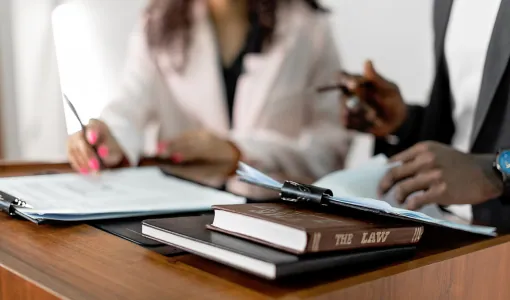 Two lawyers reviewing documents at a desk with a law book