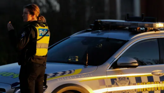 Victoria Police officer beside a highway patrol car
