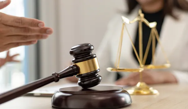 Lawyer gesturing across a desk with a gavel and scales in front