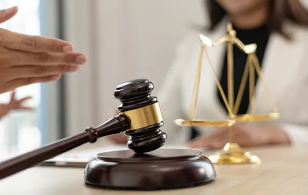 Lawyer gesturing across a desk with a gavel and scales in front
