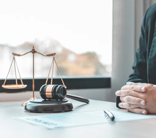Scales of justice and a gavel on a desk beside a seated client