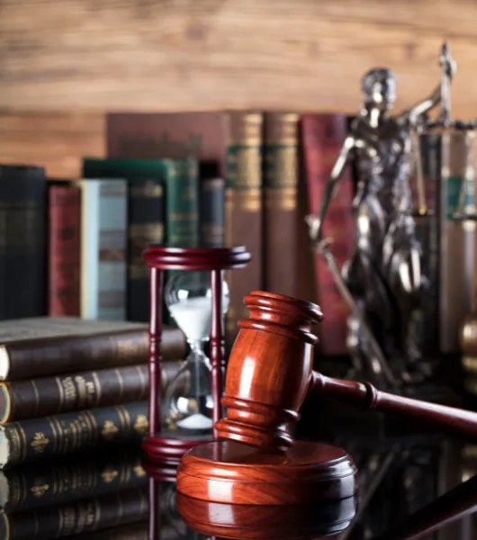 Gavel, hourglass and a statue of Justice in front of law books