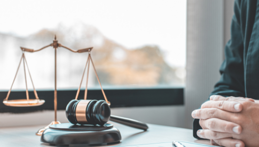 a judge sitting at a table with gavel and scales of justice