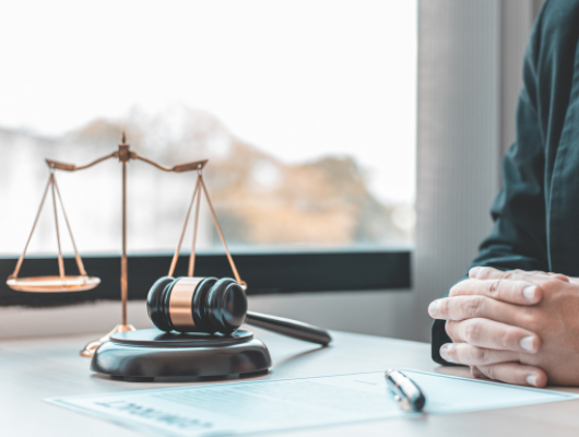 a judge sitting at a table with gavel and scales of justice